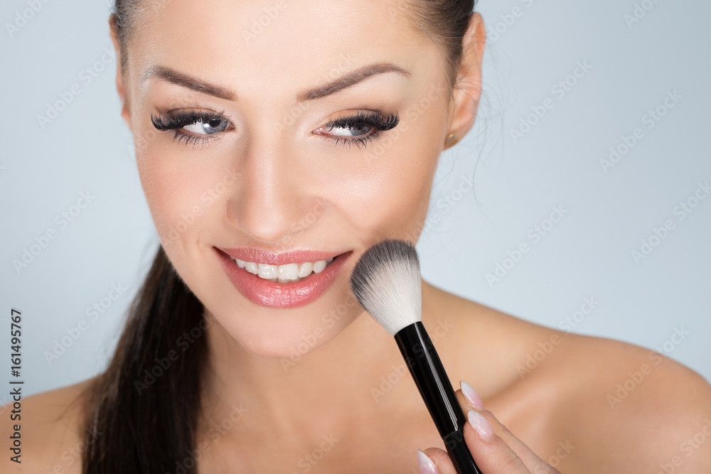 Happy beautiful woman applying face powder Happy beautiful woman applying face powder