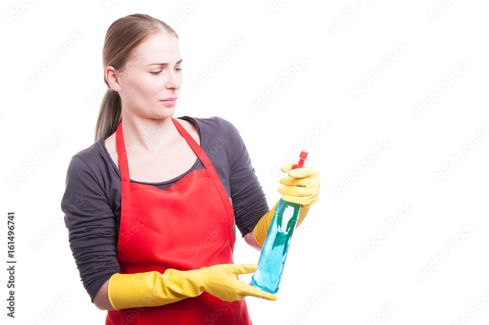 Beautiful maid in workwear looking at cleaning spray Beautiful maid in workwear looking at cleaning spray