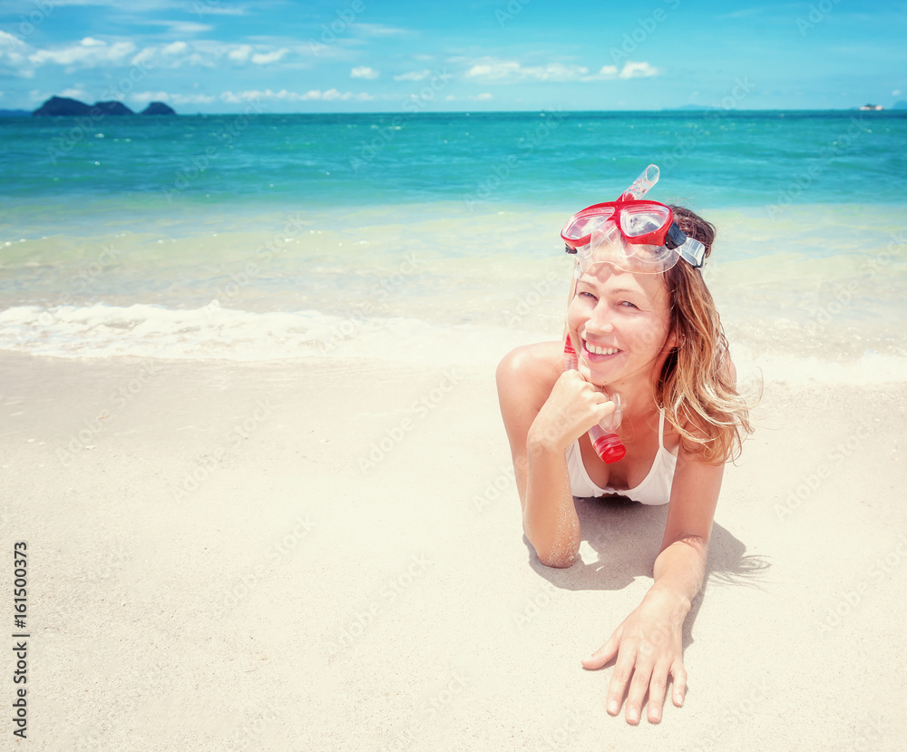 Beautiful young woman lies on a tropical beach with a snorkelling mask. Activities at the resort, sports and entertainment, vacation and travel concept Beautiful young woman lies on a tropical beach with a snorkelling mask. Activities at the resort, sports and entertainment, vacation and travel concept