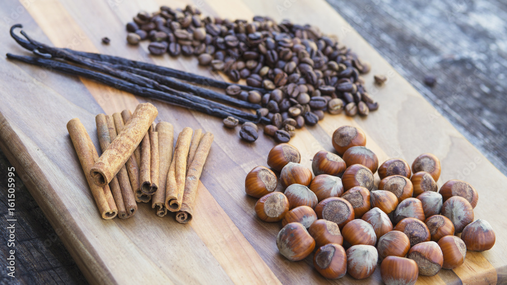 Vanilla and cinnamon sticks,with coffee beans and hazelnuts on wooden board Vanilla and cinnamon sticks,with coffee beans and hazelnuts on wooden board
