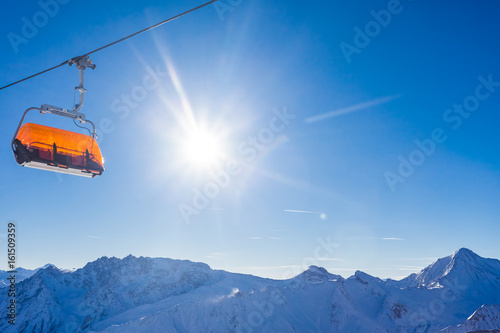 Empty chairlift panorama with mountains and blue sky in the background, snow and sun with no people, winter picture of Samnaun, Swiss Alps, Switzerland, Europe.