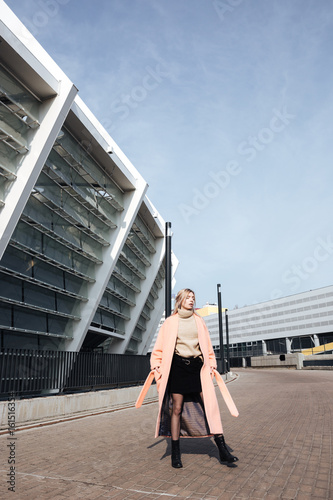 Serious young blonde lady walking outdoors. Looking aside.