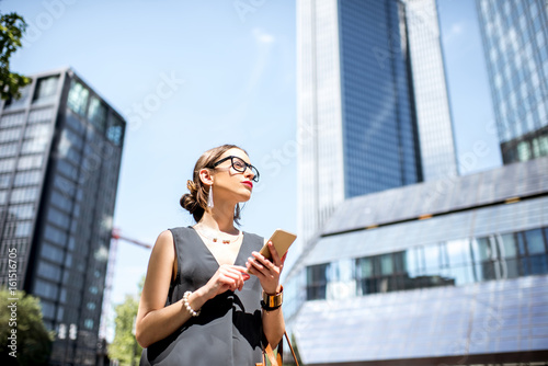 Lifestyle portrait of a businesswoman with phone in the modern district in Frankfurt city