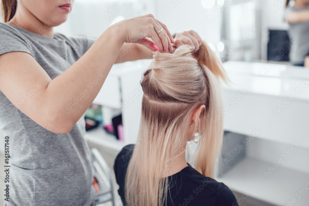 Fototapeta premium Hair stylist parting hair for styling in beauty studio.