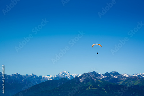 Yellow Paraglider over the Europe Alps mountains