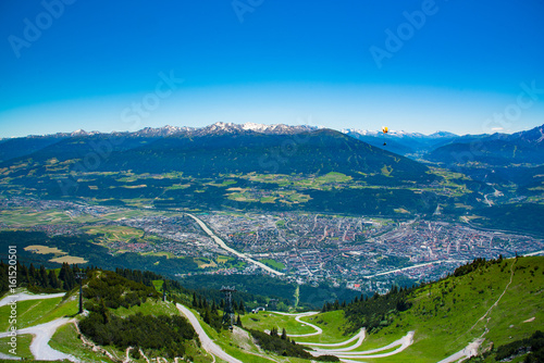 Yellow Paraglider over the Innsbruck city with Europe Alps mountains on background