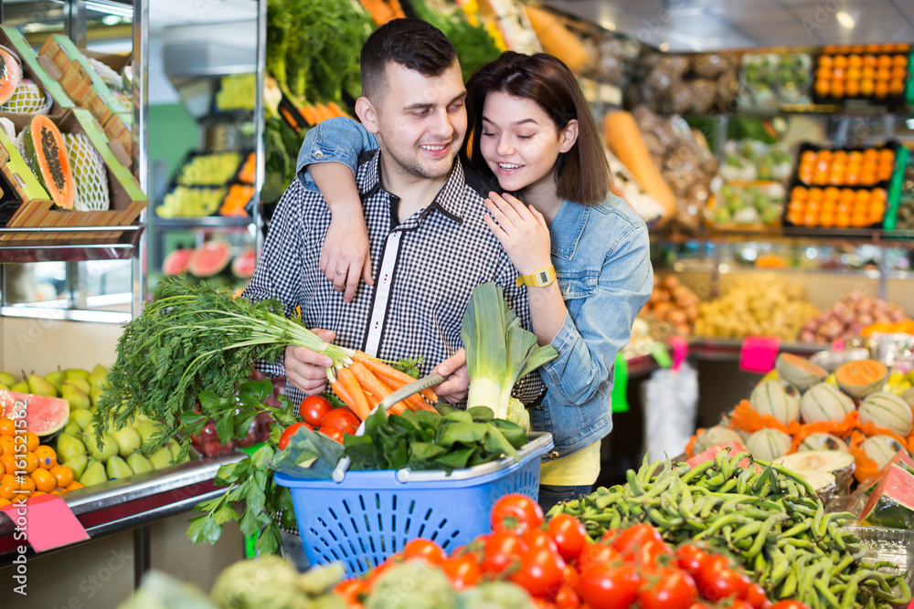 Glad couple examining various vegetables
