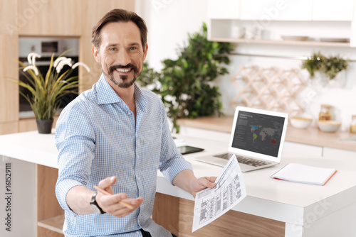 Pleasant cheerful man holding a printout