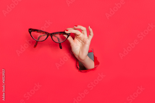 Female hand in paper hole with glasses photo
