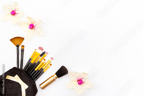 Makeup brush in my purse and some flowers Orchid on a white background. Minimal concept of beauty.
