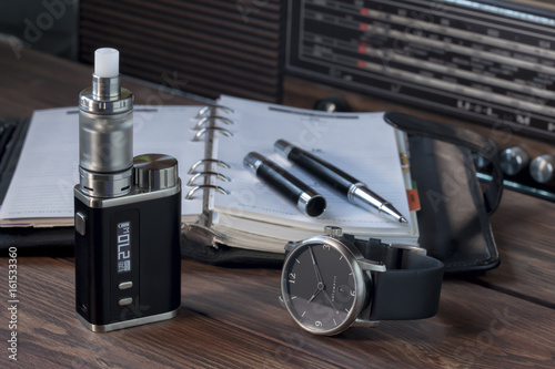 Elektrische Zigarette vor einem Terminplaner zusammen mit einer Armbanduhr