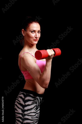 Fitness sporty smiling woman with dumbbell on a black isolation background.