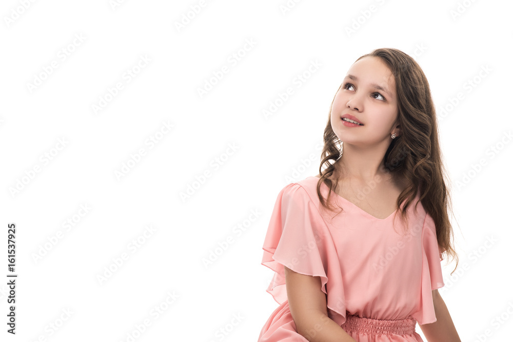 Portrait of a beautiful young girl in pink dress, isolated on white. Teenage girl smiling and looking up, right view Portrait of a beautiful young girl in pink dress, isolated on white. Teenage girl smiling and looking up, right view