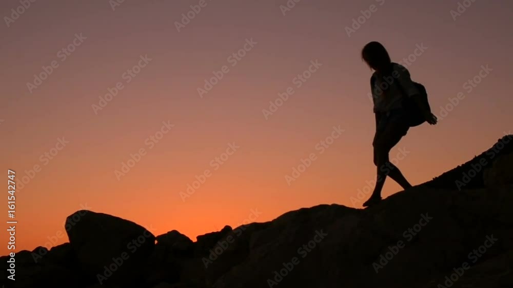 Silhouette of a female tourist who descends down the mountain, slow motion Silhouette of a female tourist who descends down the mountain, slow motion