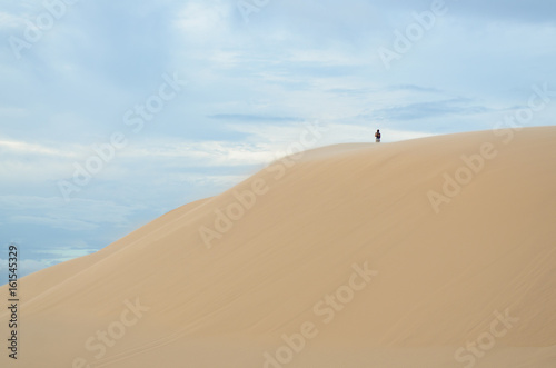 Woman standing on sand moutain, white desert, Mui Ne, Vietnam.