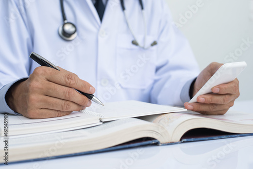 Fotografie Male doctor or medical student reading anatomy textbook