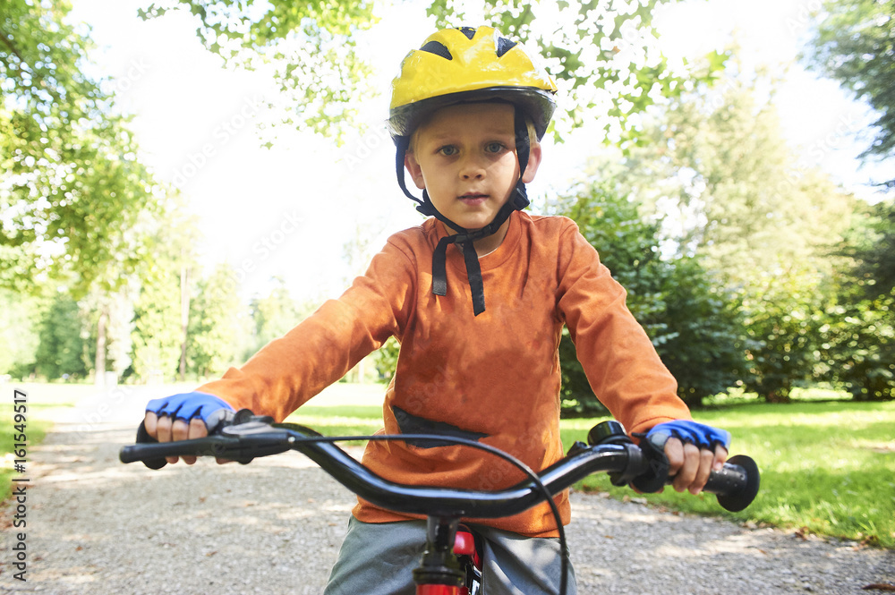 Obraz premium Boy ride a bicycle in city park 