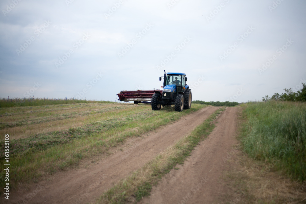 pasture mowing with blue tractor and mower