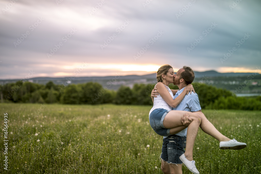 Fototapeta premium Young couple enjoying the sunset in the meadow