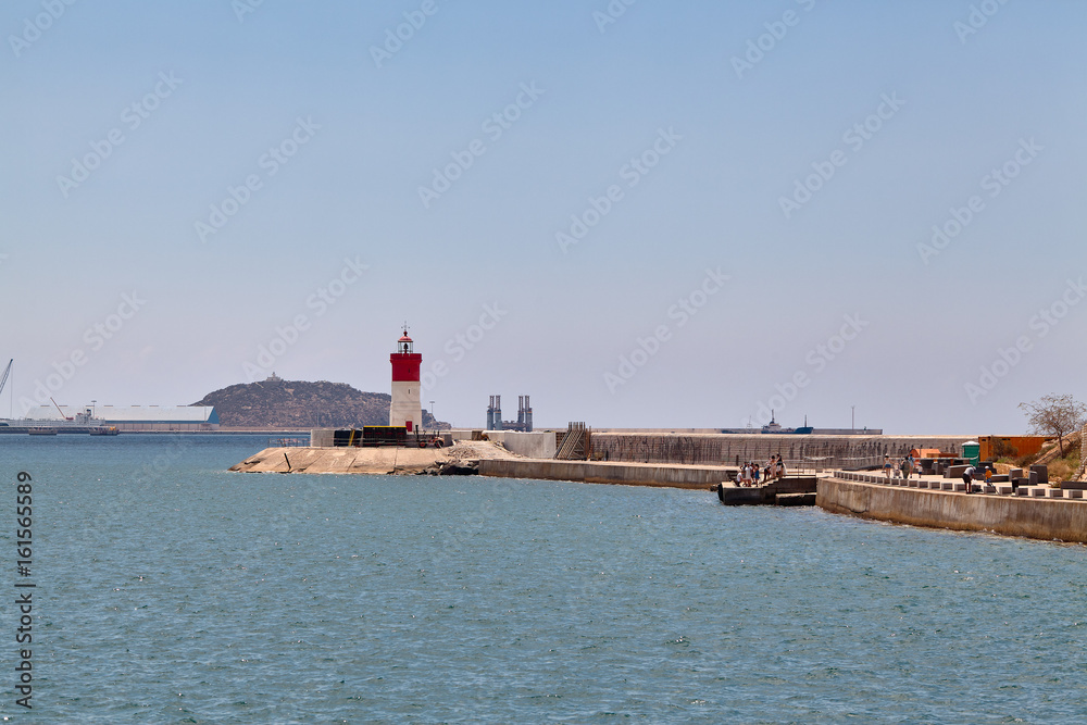 Red and white lighthouse near the fort of Christmas and the seaport. Cartagena, Spain.