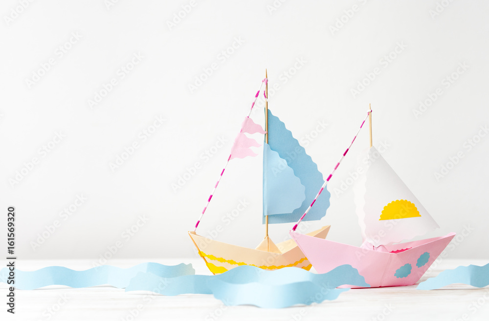 Two paper boats made of colored paper on white Two paper boats made of colored paper on white