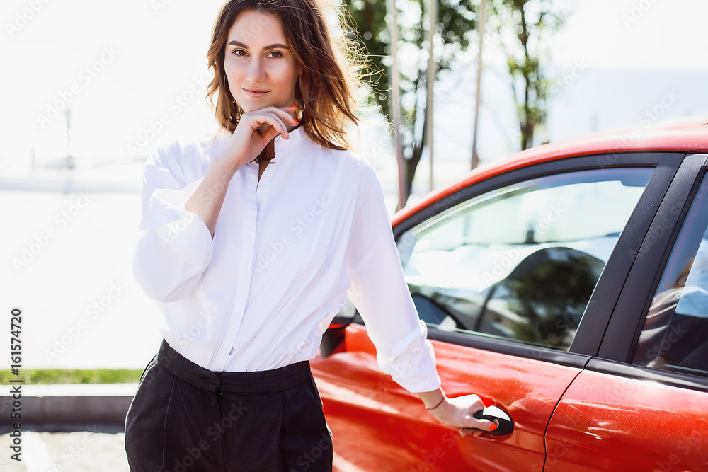 Fototapeta premium Business lady standing with car, woman in white shirt, success,happy, curly hair, manager