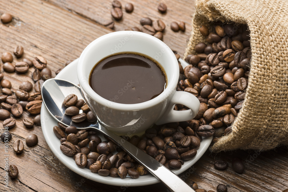 cup of coffee with burlap sack and coffee beans on wooden table. cup of coffee with burlap sack and coffee beans on wooden table.