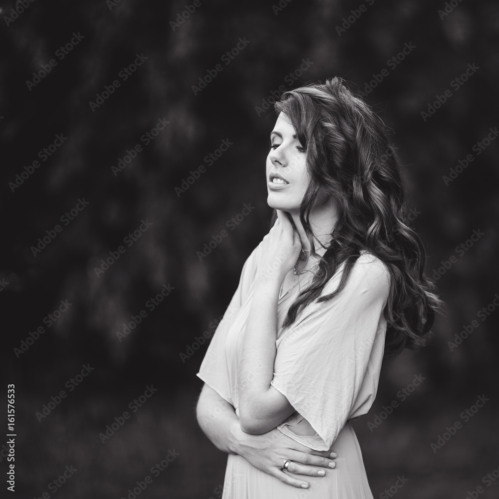 Portrait of a beautiful attractive lady of a young slender brunette girl with long dress walking through a at sunset lifestyle black and white Portrait of a beautiful attractive lady of a young slender brunette girl with long dress walking through a at sunset lifestyle black and white