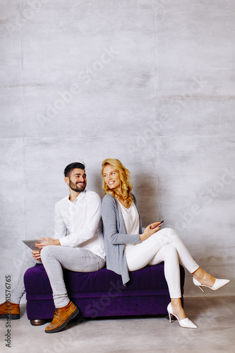 Young couple with tablet and mobile phone on sofa