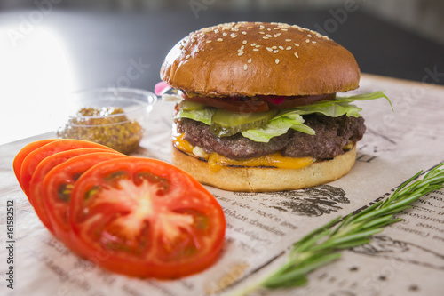 A large tasty burger with sliced tomato on a table