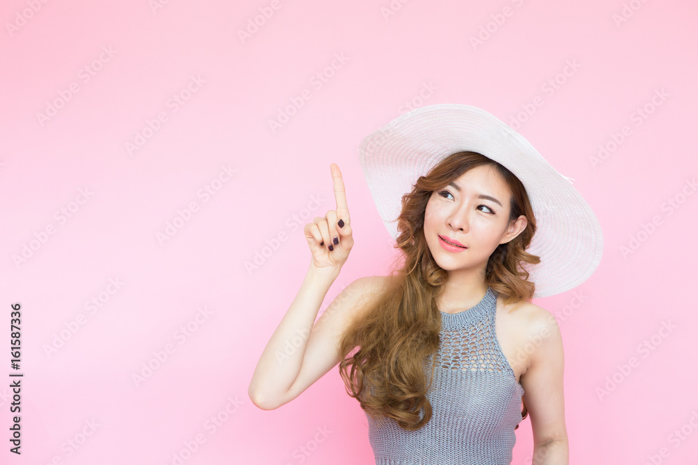 asian young woman smiling and thinking looking to the top with copy space on pink background