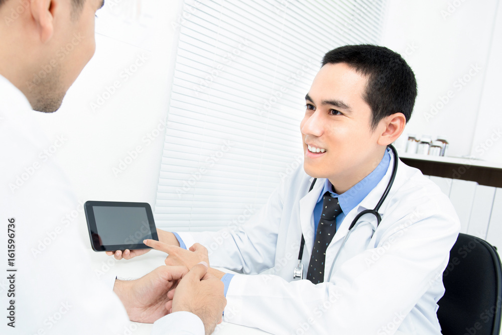 Physician talking and explaining treatment to patient by using tablet computer Physician talking and explaining treatment to patient by using tablet computer