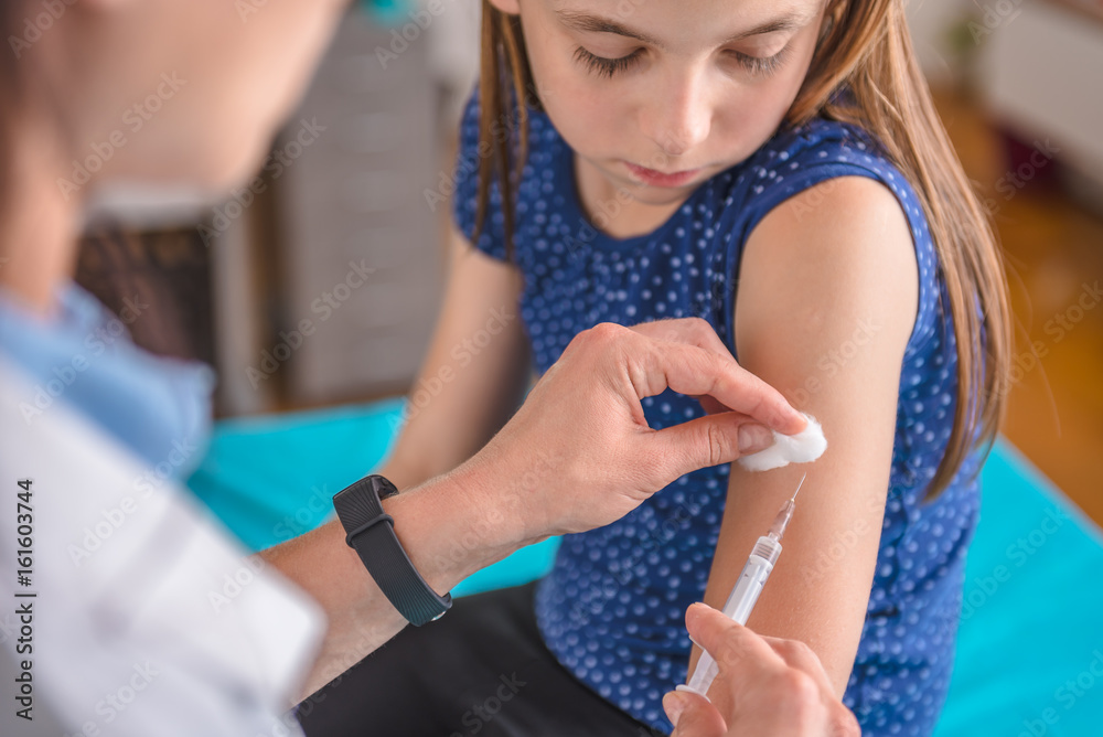 Doctor giving a young girl a vaccine shot - obrazy, fototapety, plakaty 