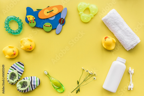 bath cosmetic set for kids, towel and toys yellow background top view space for text