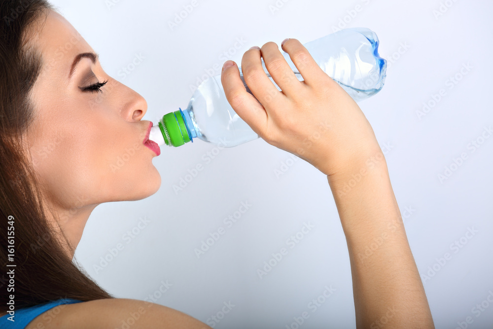 Beautiful happy woman holding and drinking water from the bottle with closed eyes. Closeup portrait. Beautiful happy woman holding and drinking water from the bottle with closed eyes. Closeup portrait.