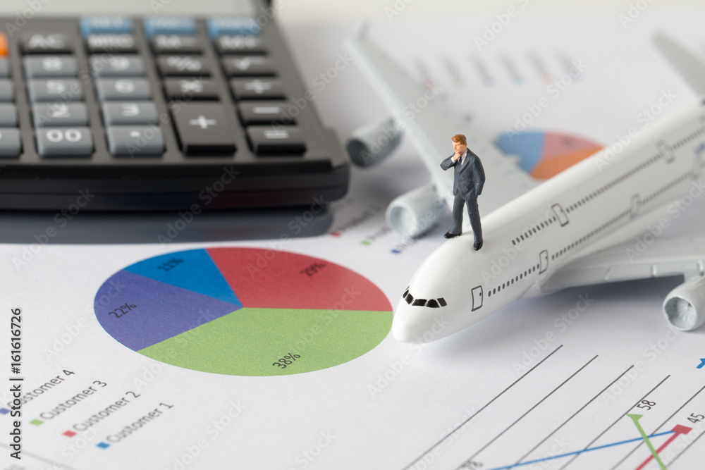 Miniature model of businessman thinking with project of airline investment standing together on paper graph. Miniature model of businessman thinking with project of airline investment standing together on paper graph.