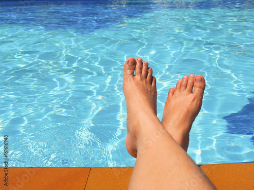 Woman's bare foot at swimming pool for summer concept.