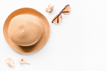 Sunglasses, summer straw hat beach and seashells on a white background with place for text