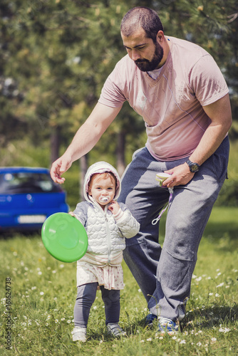 Young dad and his little daughter playing Frisbee in the park © Teodor Lazarev