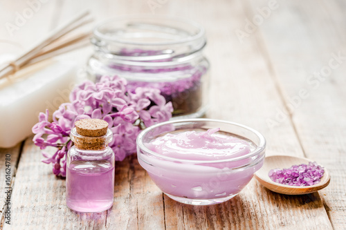 lilac cosmetics with flowers and spa set on wooden table background