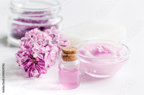 organic salt, cream, extract in lilac cosmetic set with flowers on white table background
