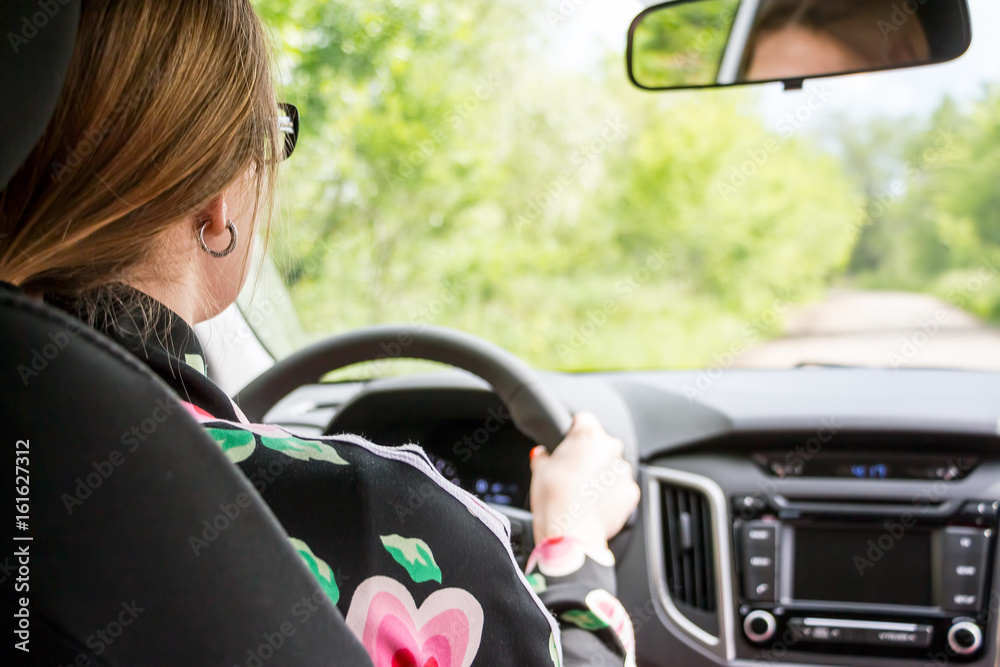Naklejka premium Girl with glasses at the wheel of the car. View from behind the seated driver