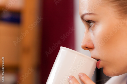 Closeup of woman drinking from white mug
