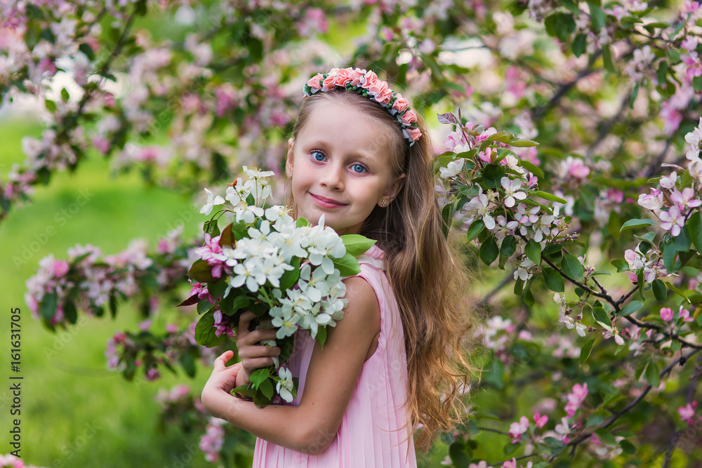 Little happy girl playing under blooming cherry tree with pink flowers. Child holding sakura blossom. Summer fun for family with kids outdoors in a beautiful spring garden. Kid with flower on Easter Little happy girl playing under blooming cherry tree with pink flowers. Child holding sakura blossom. Summer fun for family with kids outdoors in a beautiful spring garden. Kid with flower on Easter