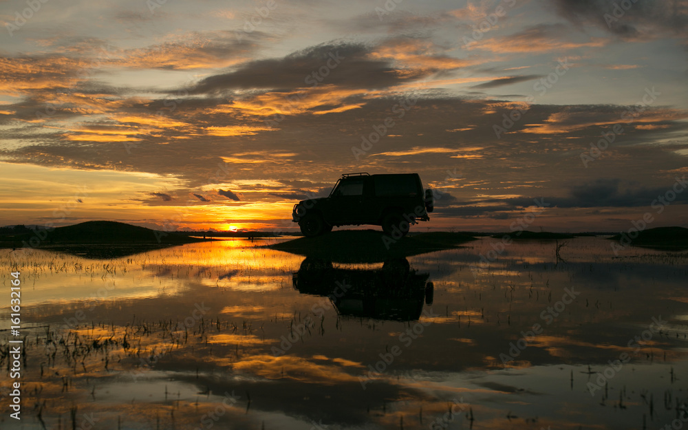 The silhouette of the car parked in the lake at sunset. With beautiful clouds in the sky On holiday travel in rainy season The silhouette of the car parked in the lake at sunset. With beautiful clouds in the sky On holiday travel in rainy season