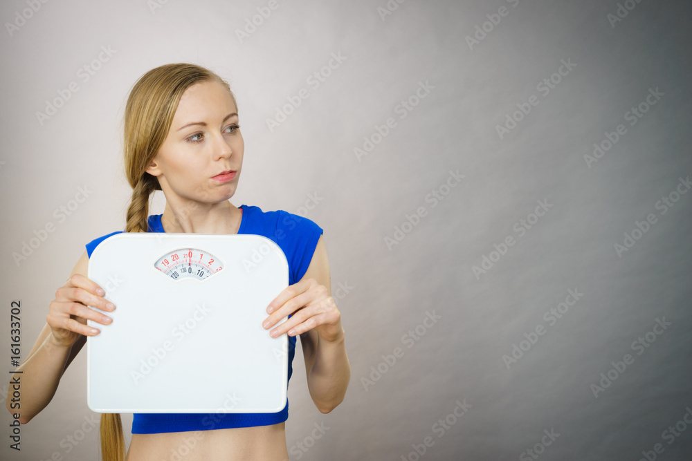 Teenage woman holding bathroom scale machine