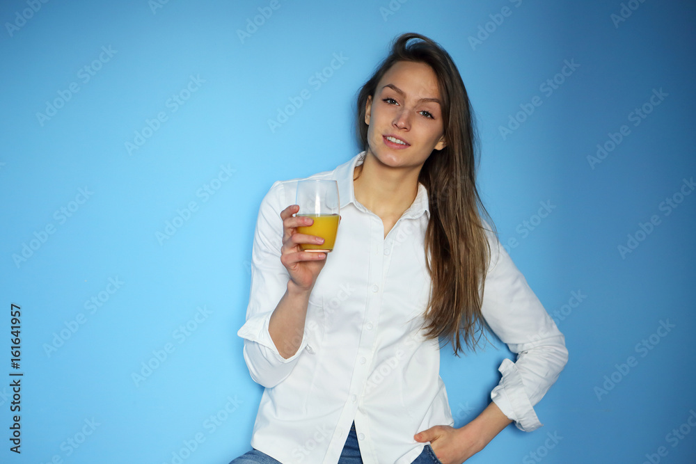 Beautiful young woman holding orange juice on a blue background, looking at the camera,healthy lifestyle Beautiful young woman holding orange juice on a blue background, looking at the camera,healthy lifestyle