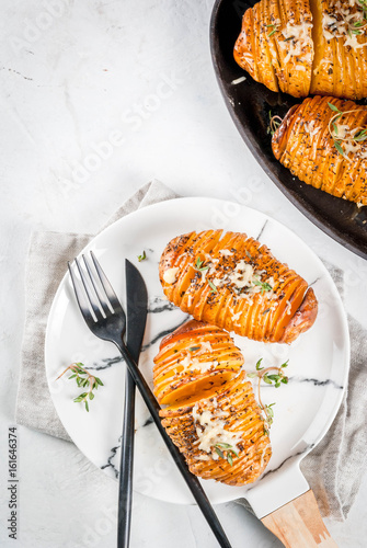 American traditional home cooking. The vegan diet. Homemade Hasselback Potato with Fresh Herbs and cheese. On white table, copy space top view photo