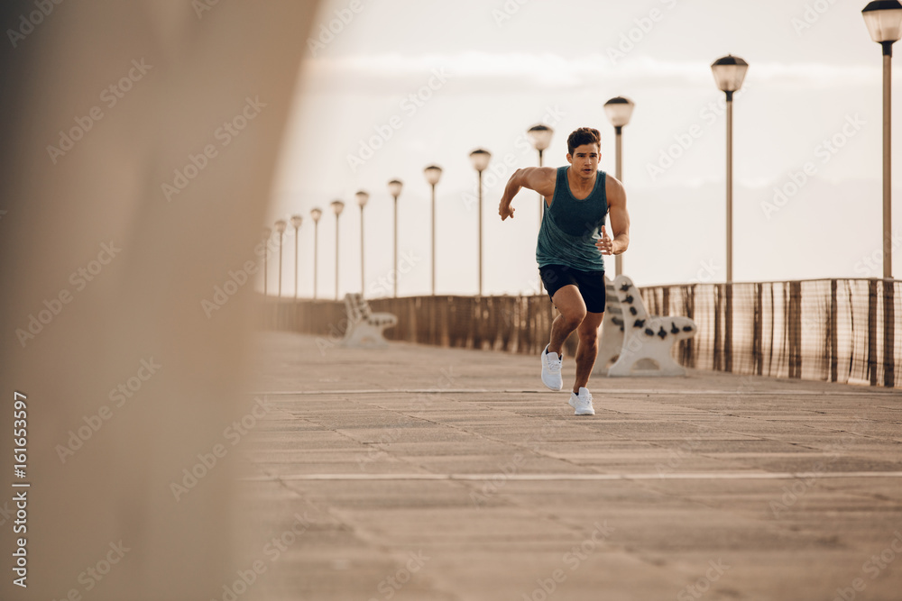Fit young man running fast on the promenade
