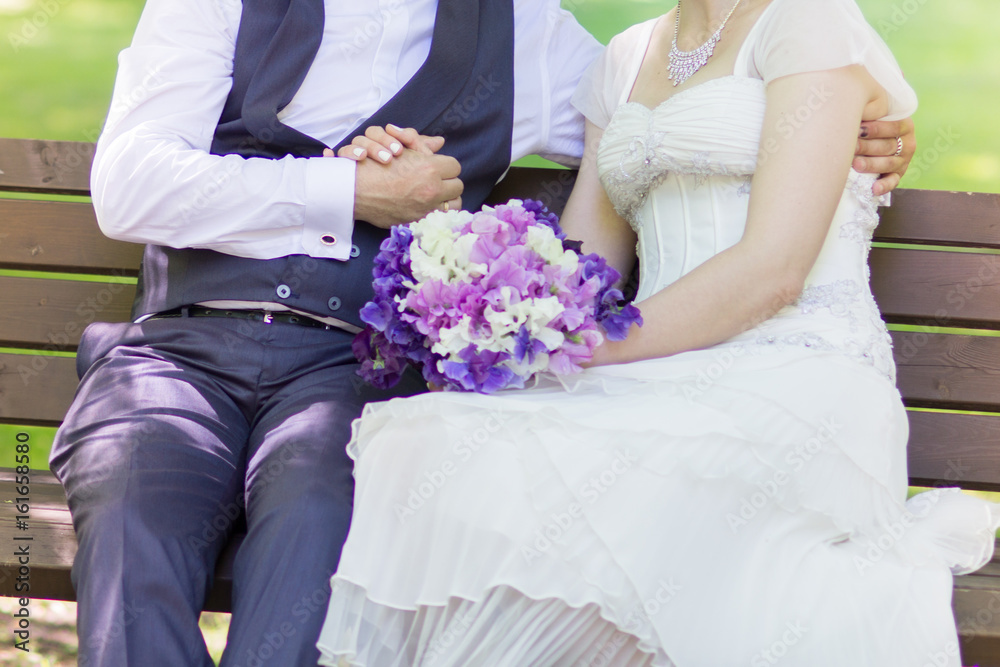 Young just married couple hugging on their wedding day with sweet pea flowers in white wedding dress and dark blue suit Young just married couple hugging on their wedding day with sweet pea flowers in white wedding dress and dark blue suit